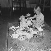 Young girl playing with her dolls, 1952 [altered from original title]